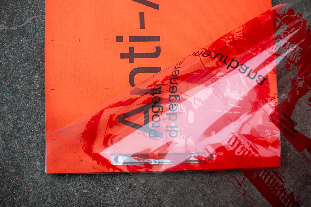 Close-up of the Anti-Atene orange cover with a transparent acetate jacket being peeled back