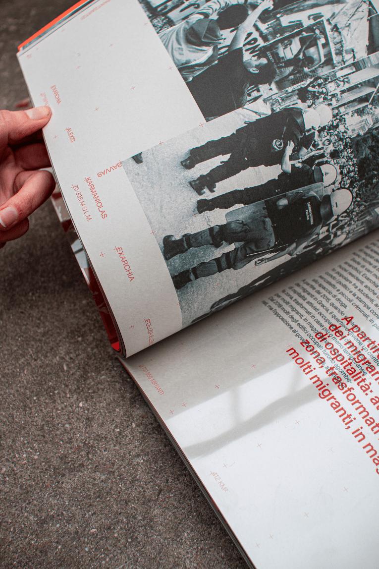 Hand leafing through the Anti-Atene book, a spread open to a section on Exarchia with black-and-white photographs of riot police and red body text