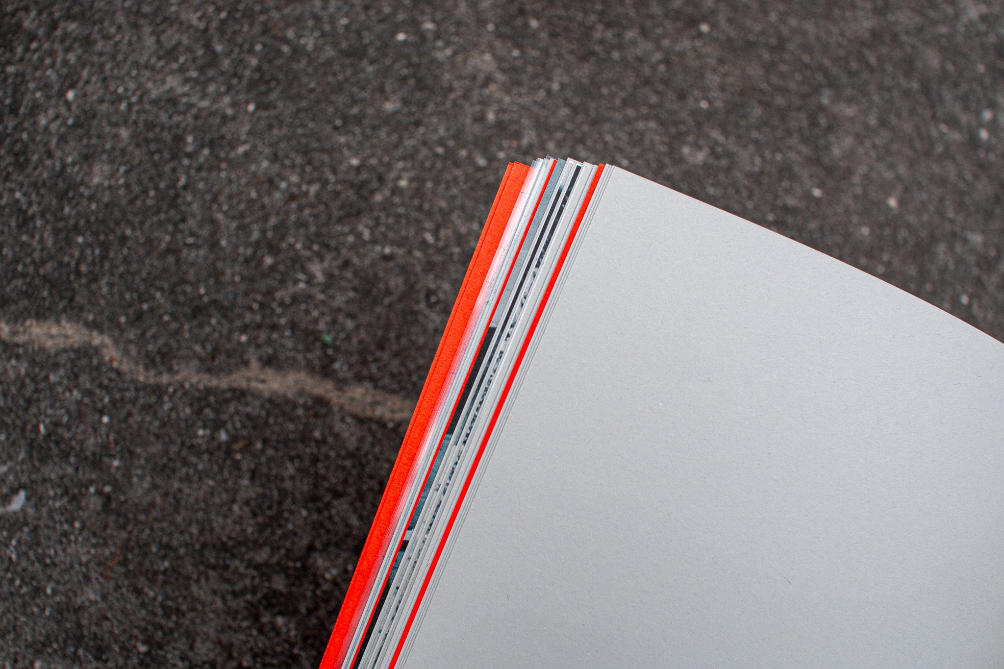 Close-up of the Anti-Atene page edges on concrete, showing the contrast between different papers used for the project