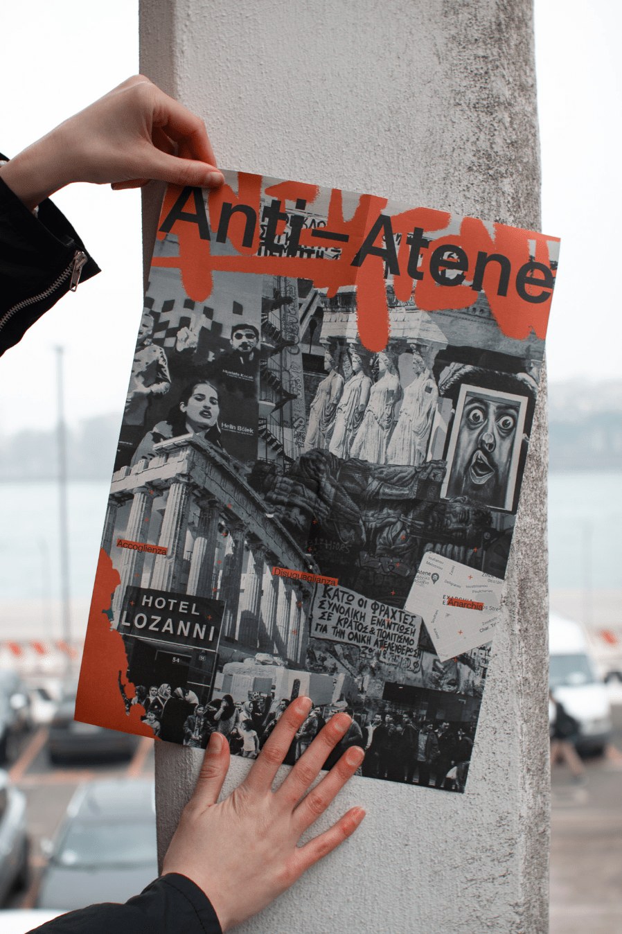 Hands pinning the Anti-Atene poster against a concrete pillar outdoors, the collage cover visible with red typographic overlays